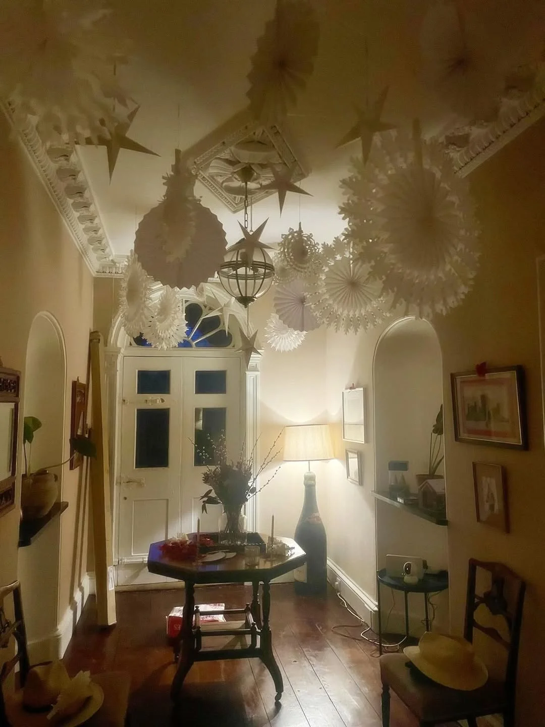 Paper snowflakes, stars and fans hung from a ceiling in a dim hallway